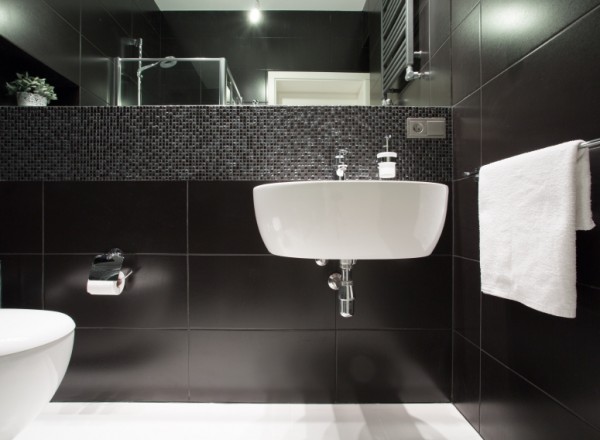 Gleich drei Fliesendesigns auf einmal sind in diesem Bad kombiniert worden: Der Kontrast von Schwarz und Weiß, kleine Mosaikfliesen und rechteckige XXL-Fliesen.