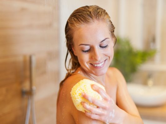 Frau wäscht sich mit Duschschwamm