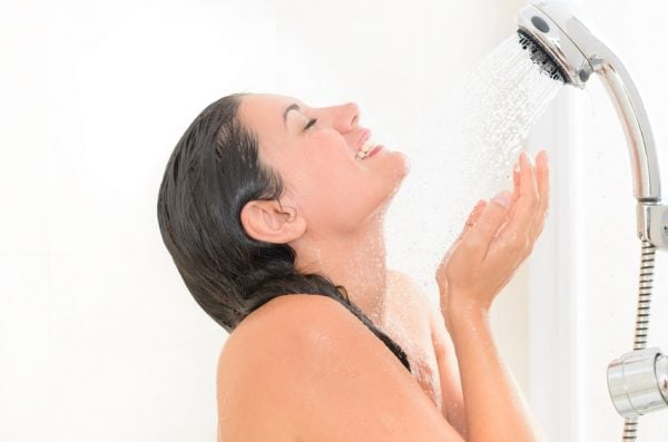 Frau wäscht Gesicht unter der Dusche