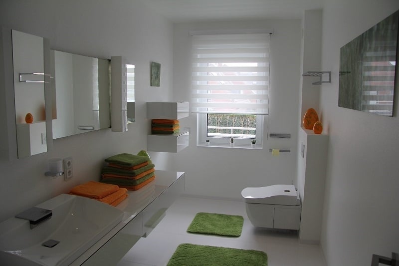Badezimmer mit Handtüchern und Teppichen in grün und orange