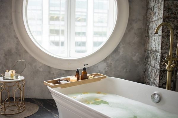 Badewanne vor rundem Fenster mit Messing Armatur