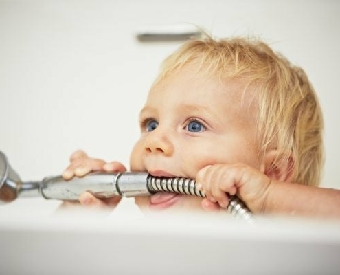 Baby in Badewanne mit Duschkopf