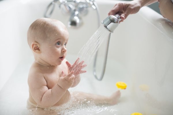Baby in Badewanne mit Duschkopf