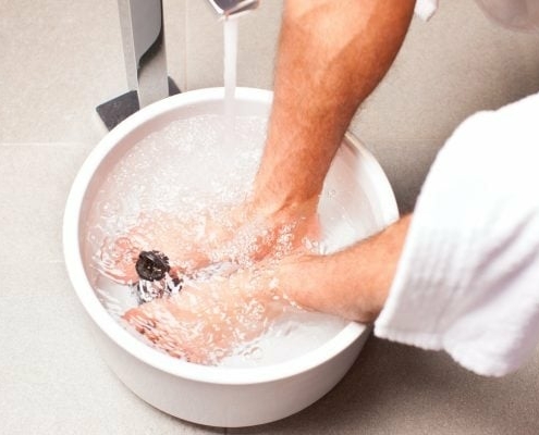 Mann nimmt ein Fußbad zuhause in einem Eimer