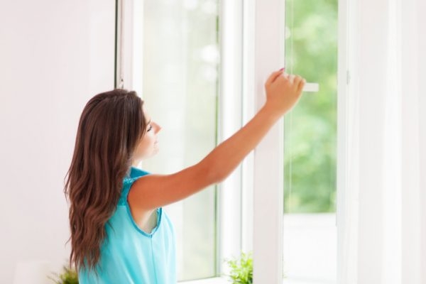 Frau öffnet das Fenster zum Lüften