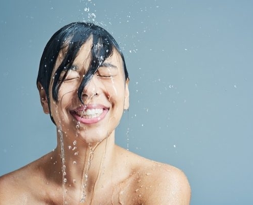 Lachende Frau wird von Wasser überschüttet