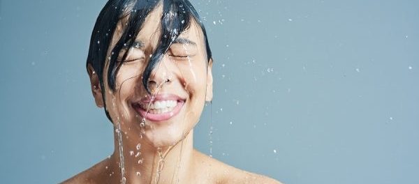 Lachende Frau wird von Wasser überschüttet