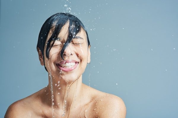 Lachende Frau wird von Wasser überschüttet