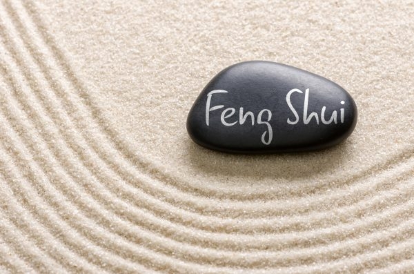 Stein mit "Feng-Shui"-Aufschrift im Sand.