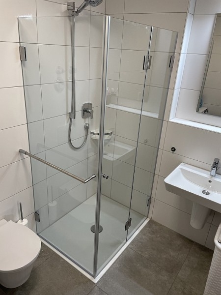 Badezimmer mit Duschwanne und Falttür