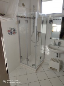Dusche mit Falttüren F1W aus Glas auf Duschwanne in weiß gefliestem Badezimmer mit Fliesendekor 