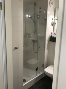 Nischendusche auf Maß M2N aus Glas auf Duschwanne in weiß gefliestem Badezimmer
